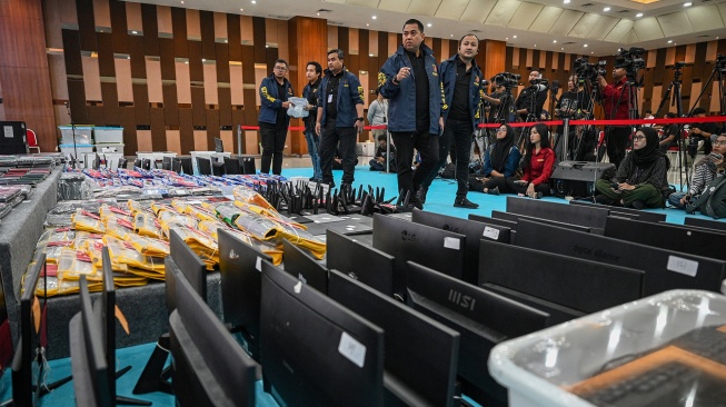 Petugas kepolisian mengecek barang bukti yang ditampilkan saat konferensi pers kasus judi online jaringan internasional, di Bareskrim Mabes Polri, Jakarta, Jumat (26/6/2026). [ANTARA FOTO/Fauzan/kye]
