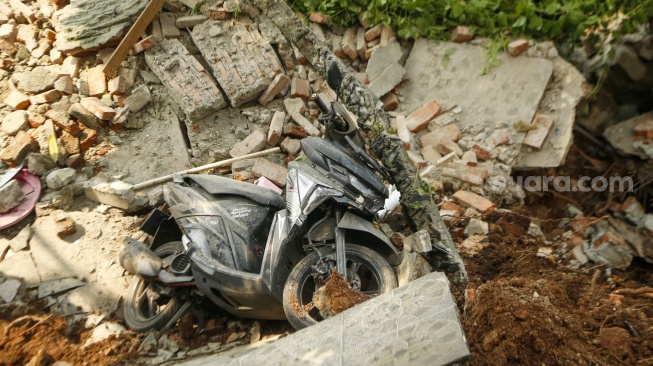 Sebuah sepeda motor berada di puing bangunan yang terdampak tanah longsor di Petamburan, Tanah Abang, Jakarta, Jumat (26/6/2026). [Suara.com/Alfian Winanto]
