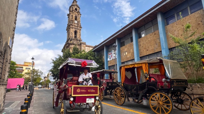 Pengemudi calandria (kereta kuda) bertenaga listrik untuk wisatawan melintasi Kuil San Jose de Gracia di kawasan Centro Historico atau Pusat Bersejarah Kota Guadalajara, Jalisco, Meksiko, Sabtu (27/6/2026) waktu setempat. [ANTARA FOTO/Aditya Pradana Putra/bar]