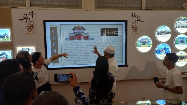 Ahung atau Imam Masjid Dongsi, Ali (berkopiah) menjelaskan sejarah Masjid Dongsi Beijing kepada rombongan dari Indonesia, Jumat (26/6/2026). [Suara.com/Eko Faizin]