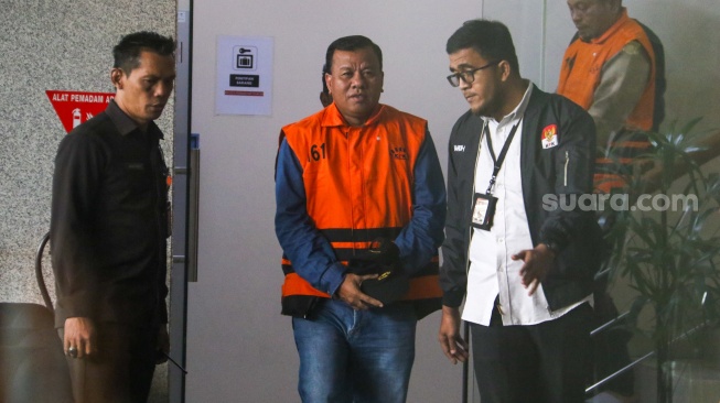 Bupati Kuantan Singingi Suhardiman Amby (tengah) berjalan menuju mobil tahanan usai menjalani pemeriksaan di Gedung Merah Putih KPK, Jakarta, Rabu (1/7/2026). [Suara.com/Alfian Winanto]
