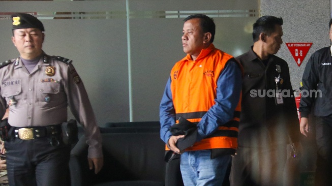 Bupati Kuantan Singingi Suhardiman Amby (tengah) berjalan menuju mobil tahanan usai menjalani pemeriksaan di Gedung Merah Putih KPK, Jakarta, Rabu (1/7/2026). [Suara.com/Alfian Winanto]
