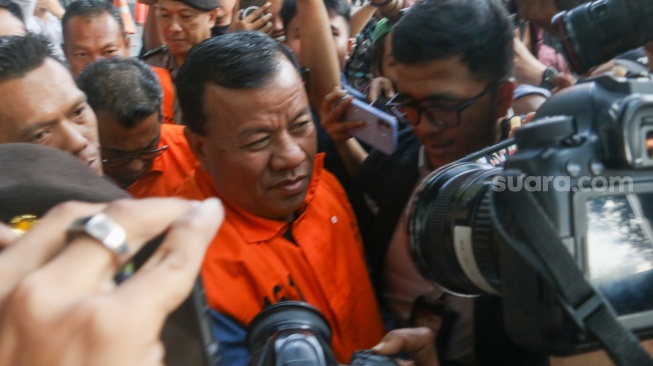 Bupati Kuantan Singingi Suhardiman Amby (tengah) berjalan menuju mobil tahanan usai menjalani pemeriksaan di Gedung Merah Putih KPK, Jakarta, Rabu (1/7/2026). [Suara.com/Alfian Winanto]
