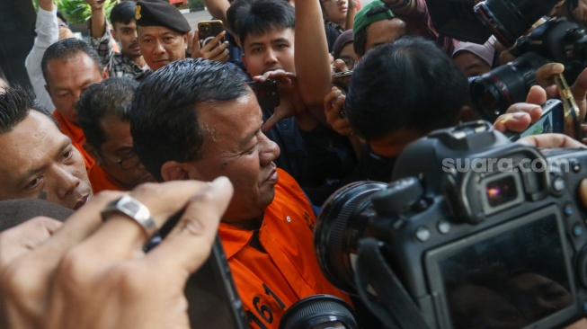 Bupati Kuantan Singingi Suhardiman Amby (tengah) berjalan menuju mobil tahanan usai menjalani pemeriksaan di Gedung Merah Putih KPK, Jakarta, Rabu (1/7/2026). [Suara.com/Alfian Winanto]
