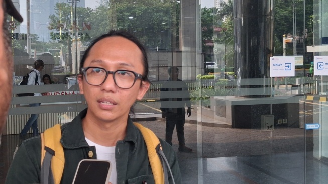 Koordinator Divisi Hukum dan Investigasi ICW, Wana Alamsyah, diwawancarai media seusai penyerahan laporan dugaan maladministrasi di depan Kantor Ombudsman RI, Jakarta, Kamis (2/7/2026) siang. [Suara.com/Cornelius Juan]