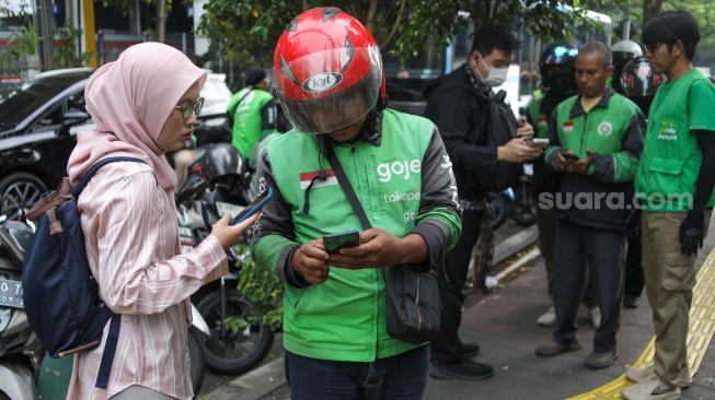 Pengemudi ojek online menjemput penumpang di seberang Stasiun Palmerah, Jakarta, Kamis (2/7/2026). [Suara.com/Alfian Winanto]