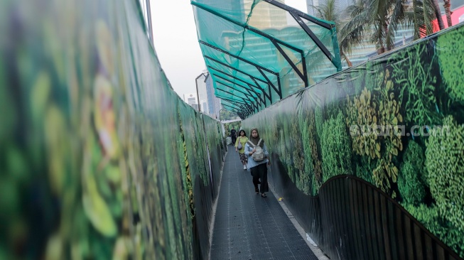Warga berjalan menyusuri jalur pedestrian darurat di kawasan Bundaran HI, Jakarta, Senin (6/7/2026). [Suara.com/Alfian Winanto]