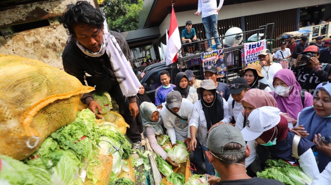 Massa aksi membagikan sayuran kepada warga saat berunjuk rasa mendukung program MBG di Jakarta, Rabu (8/7/2026). [Suara.com/Alfian Winanto]