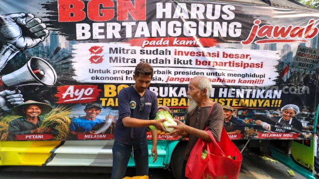 Massa aksi membagikan sayuran kepada warga saat berunjuk rasa mendukung program MBG di Jakarta, Rabu (8/7/2026). [Suara.com/Alfian Winanto]