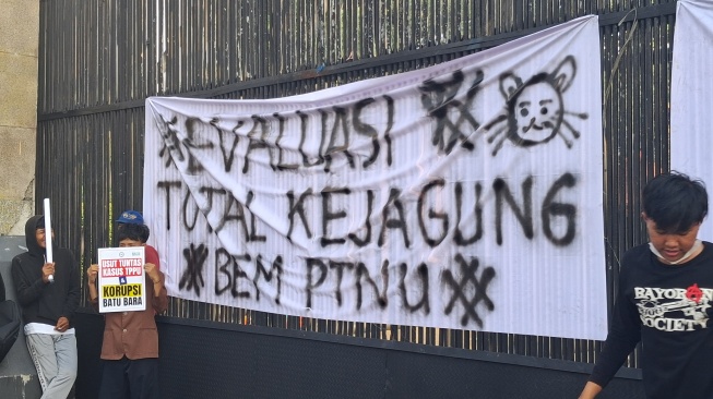 Spanduk putih bertuliskan "Evaluasi Total Kejangung" membentang pagar Gedung DPR/MPR, Senayan, Jakarta, Jumat petang (10/7/2026). [Suara.com/Cornelius Juan Prawira]