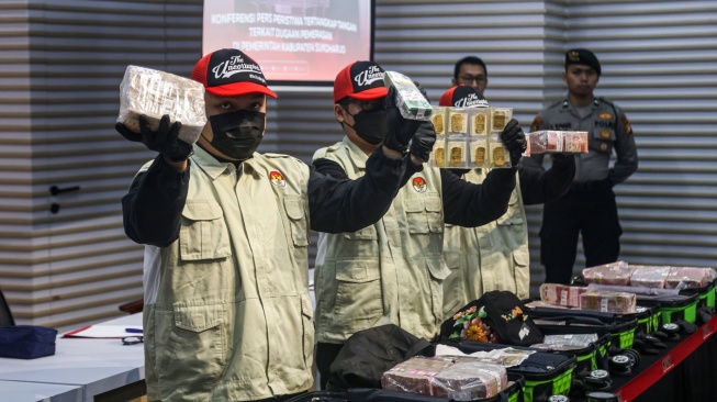 Petugas menunjukkan barang bukti saat konferensi pers operasi tangkap tangan (OTT) Bupati Sukoharjo Etik Suryani di Gedung Merah Putih KPK, Jakarta, Sabtu (11/7/2026). KPK menetapkan Bupati Sukoharjo Etik Suryani, Kepala Badan Pengelolaan Keuangan dan Aset Daerah (BPKAD) Richard Tri Handoko serta Kepala Bagian Umum Sekretariat Daerah (Setda) Kabupaten Sukoharjo Tri Mulyo sebagai tersangka dalam kasus dugaan pemerasan terhadap perangkat daerah di Kabupaten Sukoharjo dengan barang bukti berupa uang tunai Rp6,4 miliar, valuta asing senilai sekitar Rp7,5 miliar serta 25 keping logam mulia masing-masing seberat 100 gram atau total 2,5 kilogram senilai sekitar Rp7,3 miliar. (ANTARA FOTO/Darryl Ramadhan)