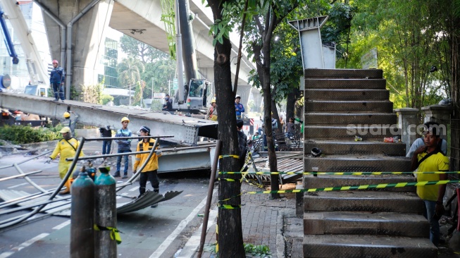 Petugas membongkar Jembatan Penyeberangan Orang (JPO) Tendean yang rusak usai tertabrak truk pengangkut alat berat di kawasan Tendean, Jakarta, Selasa (14/7/2026). [Suara.com/Alfian Winanto]