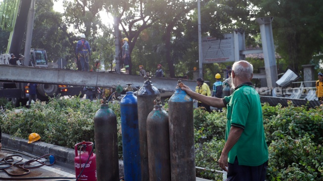 Petugas membongkar Jembatan Penyeberangan Orang (JPO) Tendean yang rusak usai tertabrak truk pengangkut alat berat di kawasan Tendean, Jakarta, Selasa (14/7/2026). [Suara.com/Alfian Winanto]