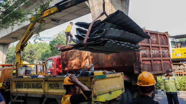 Petugas membongkar Jembatan Penyeberangan Orang (JPO) Tendean yang rusak usai tertabrak truk pengangkut alat berat di kawasan Tendean, Jakarta, Selasa (14/7/2026). [Suara.com/Alfian Winanto]