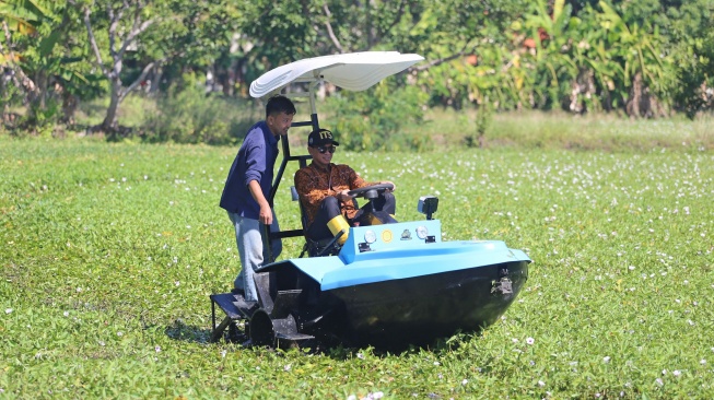 Rektor Institut Teknologi Sepuluh Nopember (ITS) Bambang Pramujati (kanan) menguji coba traktor perahu listrik di area persawahan kampus ITS, Surabaya, Jawa Timur, Selasa (14/7/2026). [ANTARA FOTO/Moch Asim/YU]