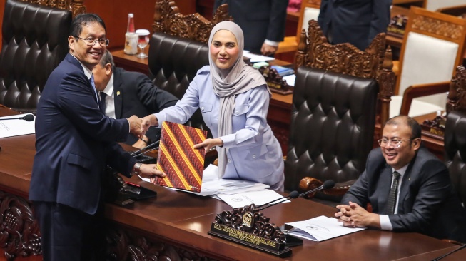 Menteri Keuangan Purbaya Yudhi Sadewa (kiri) menyerahkan berkas tanggapan pemerintah kepada Wakil Ketua DPR Sari Yuliati (tengah) dalam Rapat Paripurna ke-25 DPR Masa Persidangan V Tahun Sidang 2025-2026 di Kompleks Parlemen, Senayan, Jakarta, Selasa (14/7/2026). [ANTARA FOTO/Asprilla Dwi Adha/nym]