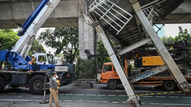 Petugas melakukan proses evakuasi truk bermuatan alat berat yang menabrak jembatan penyeberangan orang (JPO) di Jalan Kapten Tendean, Jakarta, Selasa (14/7/2026). [ANTARA FOTO/Fauzan/nym]