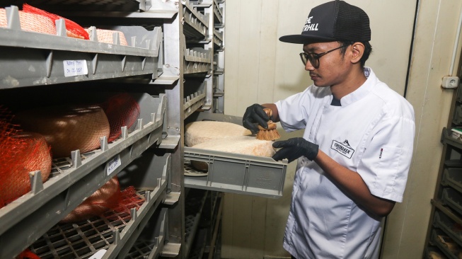Pekerja membersihkan permukaan keju artisan saat proses pematangan (aging) di Mazaraat Artisan Cheese Factory, Cangkringan, Sleman, DI Yogyakarta, Selasa (14/7/2026). [ANTARA FOTO/Rahid Putra Laksana/agr]
