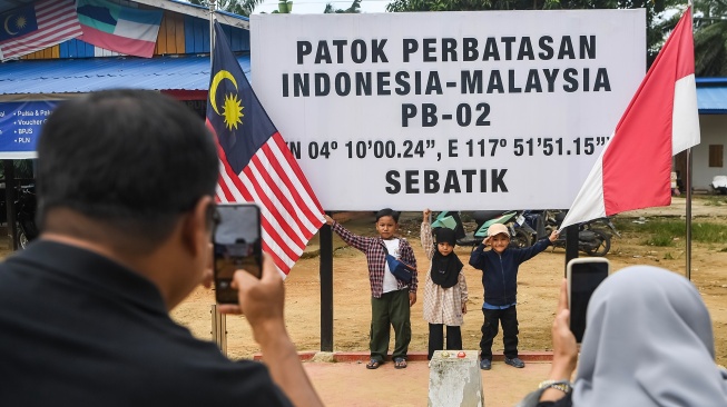 Sejumlah warga Nunukan berfoto di depan patok dua perbatasan Indonesia-Malaysia di Desa Aji Kuning, Kecamatan Sebatik Tengah, Kabupaten Nunukan, Kalimantan Utara, Minggu (19/7/2026). [ANTARA FOTO/M Risyal Hidayat/wsj]