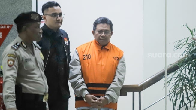 Bupati Lombok Barat Lalu Ahmad Zaini berjalan menuju mobil tahanan usai menjalani pemeriksaan di Gedung Merah Putih KPK, Jakarta, Selasa (21/7/2026). [Suara.com/Alfian Winanto]
