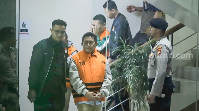 Bupati Lombok Barat Lalu Ahmad Zaini berjalan menuju mobil tahanan usai menjalani pemeriksaan di Gedung Merah Putih KPK, Jakarta, Selasa (21/7/2026). [Suara.com/Alfian Winanto]