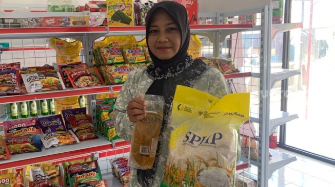 Yunita selaku pengurus KDMP Tamanmartani bagian Gerai Sembako menunjukkan minyak goreng dan berat yang dipasok ke toko kelontong. (Suara.com/Irwan Febri)