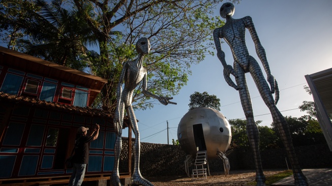 Pengunjung memotret karya yang dipamerkan saat Cosmos Exhibition di Kampung Alien, Nanggulan, Kulon Progo, D.I Yogyakarta, Selasa (21/7/2026). [ANTARA FOTO/Andreas Fitri Atmoko/sgd]