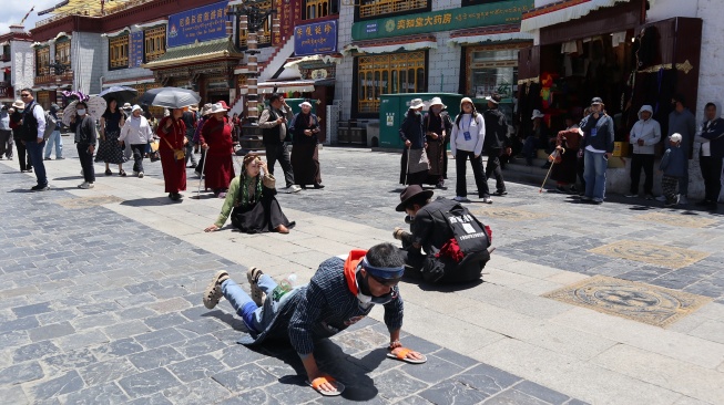 Peziarah melakukan ritual ibadah dengan berlutut hingga tengkurap ke tanah di Jalan Barkhor di kota Lhasa, Daerah Otonom Xizang pada Selasa (21/7/2026). [ANTARA FOTO/Desca Lidya Natalia/bar]
