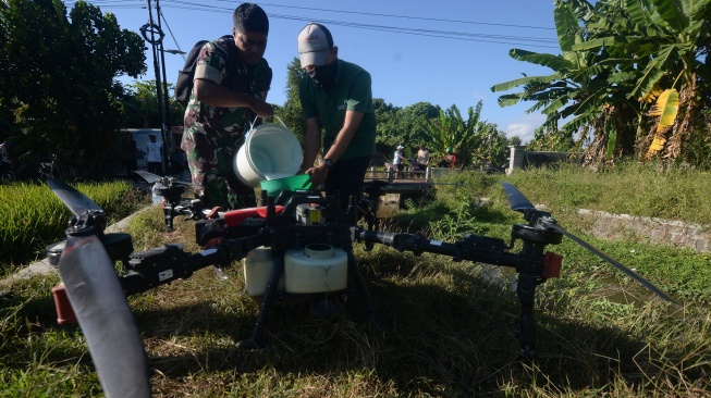 Prajurit TNI membantu memasukkan cairan pestisida ke dalam tangki pesawat tanpa awak atau drone pertanian saat gerakan pengendalian hama terpadu wereng batang coklat di Batan, Banyudono, Boyolali, Jawa Tengah, Rabu (22/7/2026). [ANTARA FOTO/Aloysius Jarot Nugroho/bar]