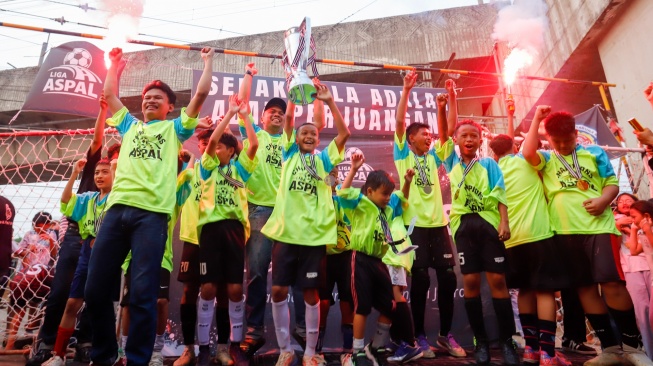 Para pemain dari tim Blue Lion mengangkat trofi usai menjuarai Liga Aspal 2026. [Suara.com/Alfian Winanto]