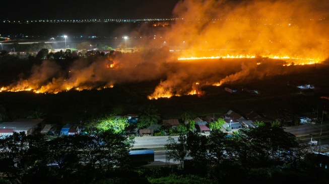 Foto udara api membakar lahan yang berada di sisi gerbang tol kramasan di Desa Ibul Besar I, Pemulutan, Ogan Ilir (OI), Sumatera Selatan, Minggu (26/7/2026). [ANTARA FOTO/Nova Wahyudi]
