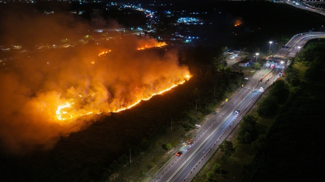Foto udara api membakar lahan yang berada di sisi gerbang tol kramasan di Desa Ibul Besar I, Pemulutan, Ogan Ilir (OI), Sumatera Selatan, Minggu (26/7/2026). [ANTARA FOTO/Nova Wahyudi]