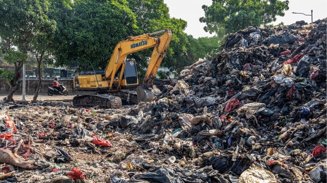 Pengendara sepeda motor melintas di dekat tumpukan sampah di Jalan Kepanduan II, Penjaringan, Jakarta, Senin (27/7/2026). [ANTARA FOTO/Rakha Raditya Yahya/tom]