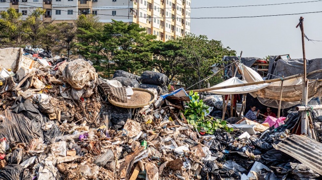 Pemulung duduk di dekat tumpukan sampah di Jalan Kepanduan II, Penjaringan, Jakarta, Senin (27/7/2026). [ANTARA FOTO/Rakha Raditya Yahya/tom]
