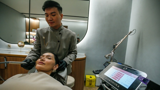 Seorang tenaga medis melakukan perawatan wajah menggunakan alat berbasis teknologi kepada pelanggan di sebuah klinik Dermalift di Jakarta, Senin (28/7/2026). [Handout]

