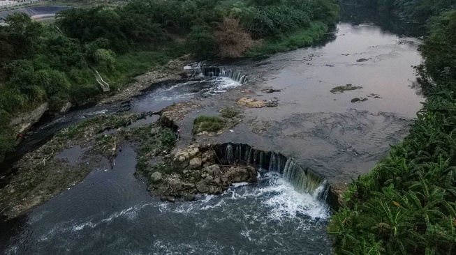 Foto udara aliran Sungai Cileungsi yang airnya berwarna hitam diduga akibat tercemar limbah di Curug Parigi, Cikiwul, Bantargebang, Kota Bekasi, Jawa Barat, Rabu (5/8/2026). [ANTARA FOTO/Darryl Ramadhan/foc]

