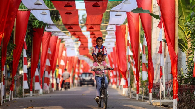 Anak-anak bersepeda di bawah bendera Merah Putih yang terbentang di Kampung Peundeuy Timur, Desa Karang Satu, Kecamatan Karangbahagia, Kabupaten Bekasi, Jawa Barat, Kamis (6/8/2026). [ANTARA FOTO/Darryl Ramadhan/kye]