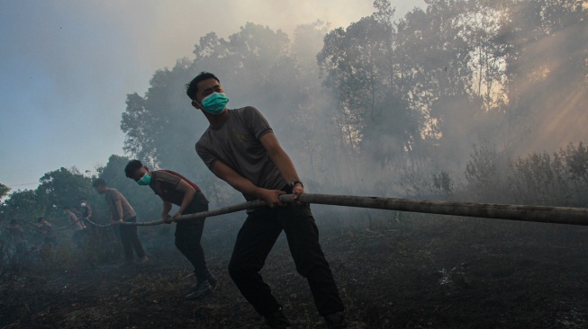 Personel polisi menarik selang air saat berupaya memadamkan kebakaran lahan di dekat kawasan permukiman Tegal Sari, Palangka Raya, Kalimantan Tengah, Jumat, (7/8/2026). [ANTARA FOTO/Auliya Rahman/hma]