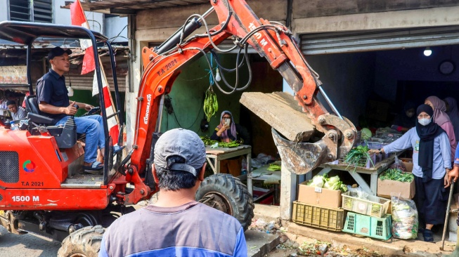 Petugas melakukan penataan drainase di Pasar Cisalak, Kota Depok Jawa Barat, Selasa (11/8/2026). [Suara.com/Alfian Winanto]
