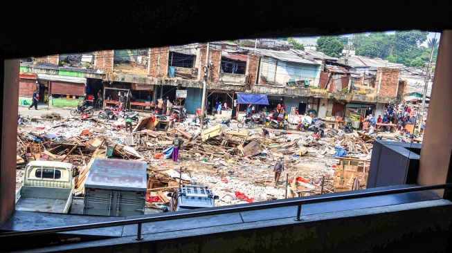 Pedagang mengangkut sisa material bangunan dari lapak yang dirobohkan di proyek penataan Pasar Cisalak, Kota Depok Jawa Barat, Selasa (11/8/2026). [Suara.com/Alfian Winanto]