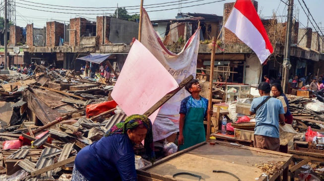 Pedagang mengangkut sisa material bangunan dari lapak yang dirobohkan di proyek penataan Pasar Cisalak, Kota Depok Jawa Barat, Selasa (11/8/2026). [Suara.com/Alfian Winanto]