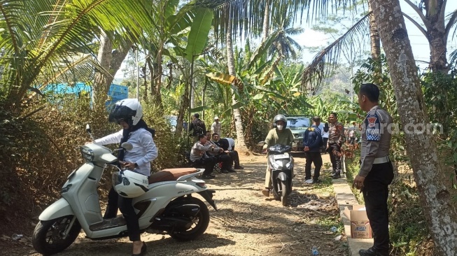 Pihak kepolisian melakukan penjagaan di sekitar Tempat Pemakaman Umum (TPU) Bantaragung, tempat peristirahatan terakhir Sutrimo, saat petugas tengah melakukan proses ekshumasi (pembongkaran makam). (Suara.com/Adi Kurniawan)