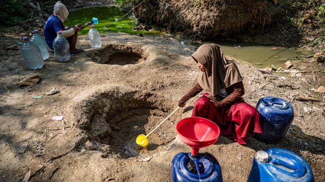 Sejumlah warga mengambil air dari belik yang dibuat di dasar sungai yang mengering di Dusun Ngedat, Desa Ketro, Grobogan, Jawa Tengah, Kamis (13/8/2026). [ANTARA FOTO/Aprillio Akbar/kye]