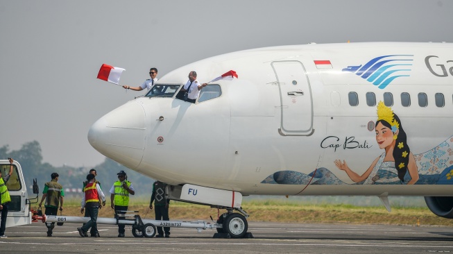 Pilot pesawat Boeing 737-800 milik maskapai Garuda Indonesia mengibarkan bendera Merah Putih saat mendarat di Bandara Husein Sastranegara, Bandung, Jawa Barat, Jumat (14/8/2026). [ANTARA FOTO/Raisan Al Farisi/kye]
