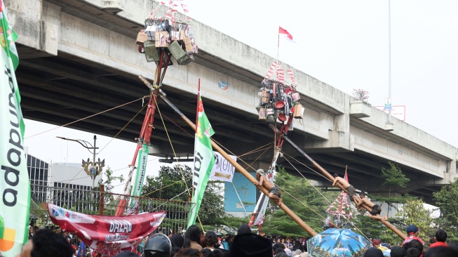 Peserta mengikuti lomba memanjat pohon pinang di Semarak Kalimalang 2026 di Jakarta, Senin (17/8/2026). [Suara.com/Novi]

