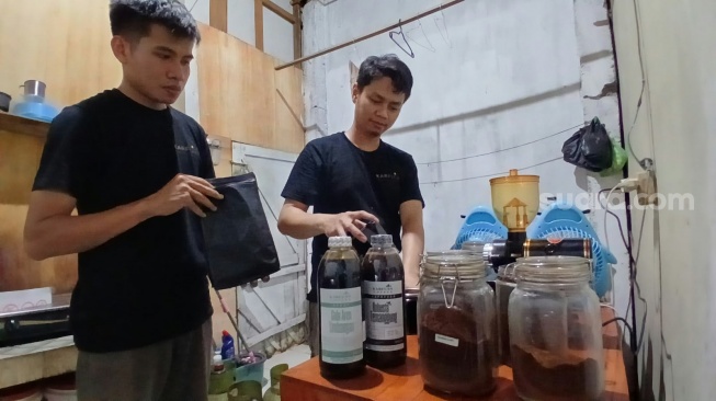 Owner Karfuan Coffee, Ari Purwanto (kiri) memproduksi kopi konsentrat. [Suara.com/Budi Arista Romadhoni]