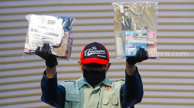 Petugas menunjukan barang bukti berupa uang tunai dari hasil Operasi Tangkap Tangan (OTT) saat konferensi pers terkait kasus korupsi Penerimaan Mahasiswa Baru di Universitas Jenderal Soedirman (Unsoed) Purwokerto di Gedung Merah Putih KPK, Jakarta, Jumat (21/8/2026). [Suara.com/Alfian Winanto]