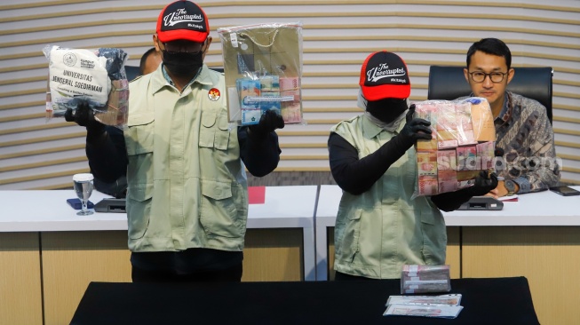 Petugas menunjukan barang bukti berupa uang tunai dari hasil Operasi Tangkap Tangan (OTT) saat konferensi pers terkait kasus korupsi Penerimaan Mahasiswa Baru di Universitas Jenderal Soedirman (Unsoed) Purwokerto di Gedung Merah Putih KPK, Jakarta, Jumat (21/8/2026). [Suara.com/Alfian Winanto]