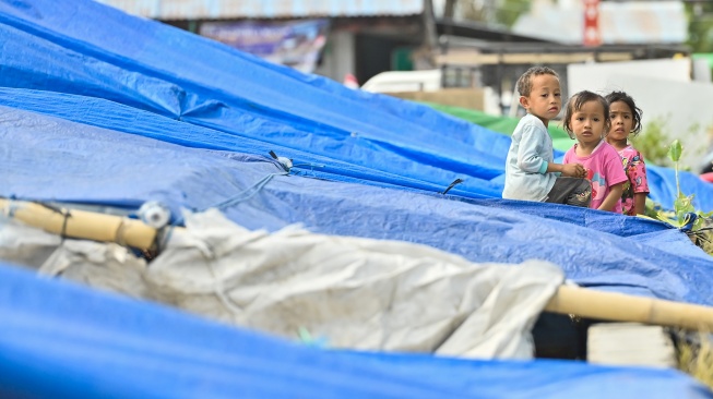 Tiga anak bermain di posko pengungsian Lapangan Barangkolong, Reo, Kabupaten Manggarai, NTT, Kamis (20/8/2026). [ANTARA FOTO/Fikri Yusuf/nym]