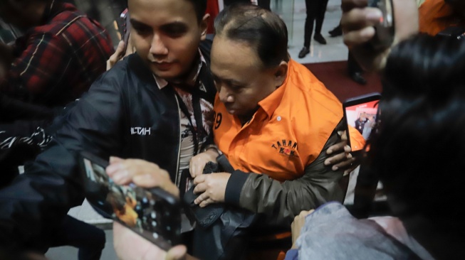 Rektor Universitas Jenderal Soedirman (Unsoed)  bersama tersangka lainnya berjalan menuju mobil tahanan usai menjalani pemeriksaan pasca terjaring operasi tangkap tangan (OTT) di Gedung KPK, Jakarta, Sabtu (22/8/2026) dini hari. [Suara.com/Alfian Winanto]
